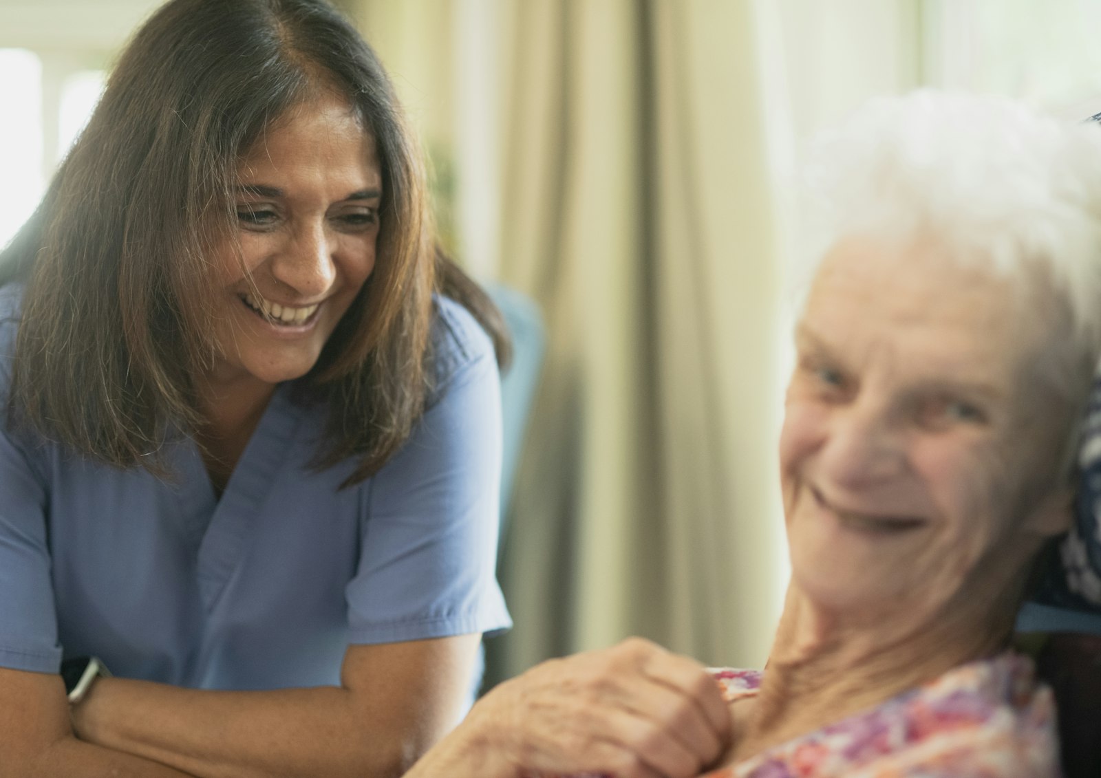 Une soignante souriante auprès d’une patiente âgée